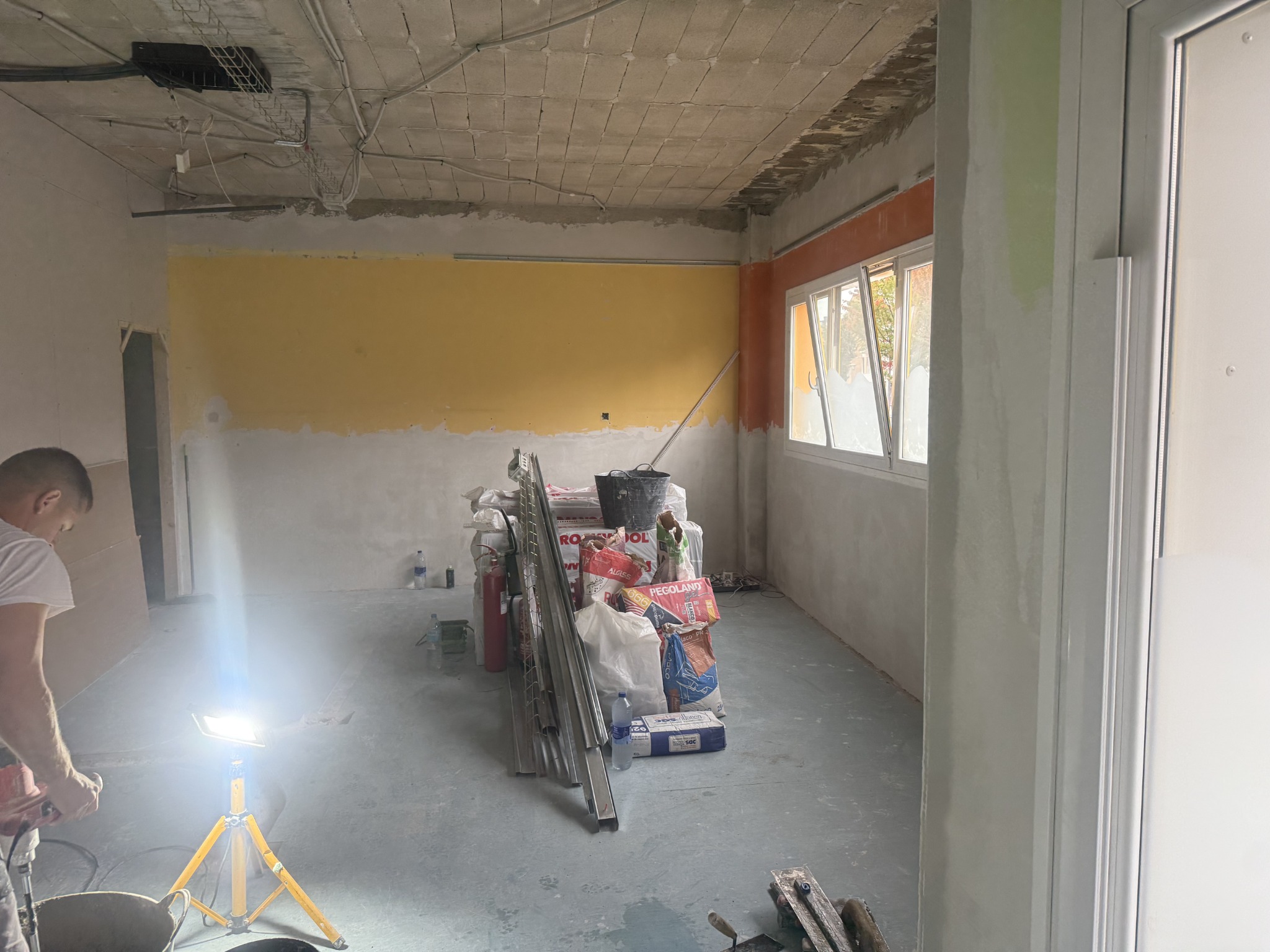 Sala principal con ventanas y materiales durante la reforma de la oficina